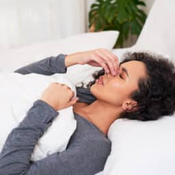 Woman touches nose while trying to sleep