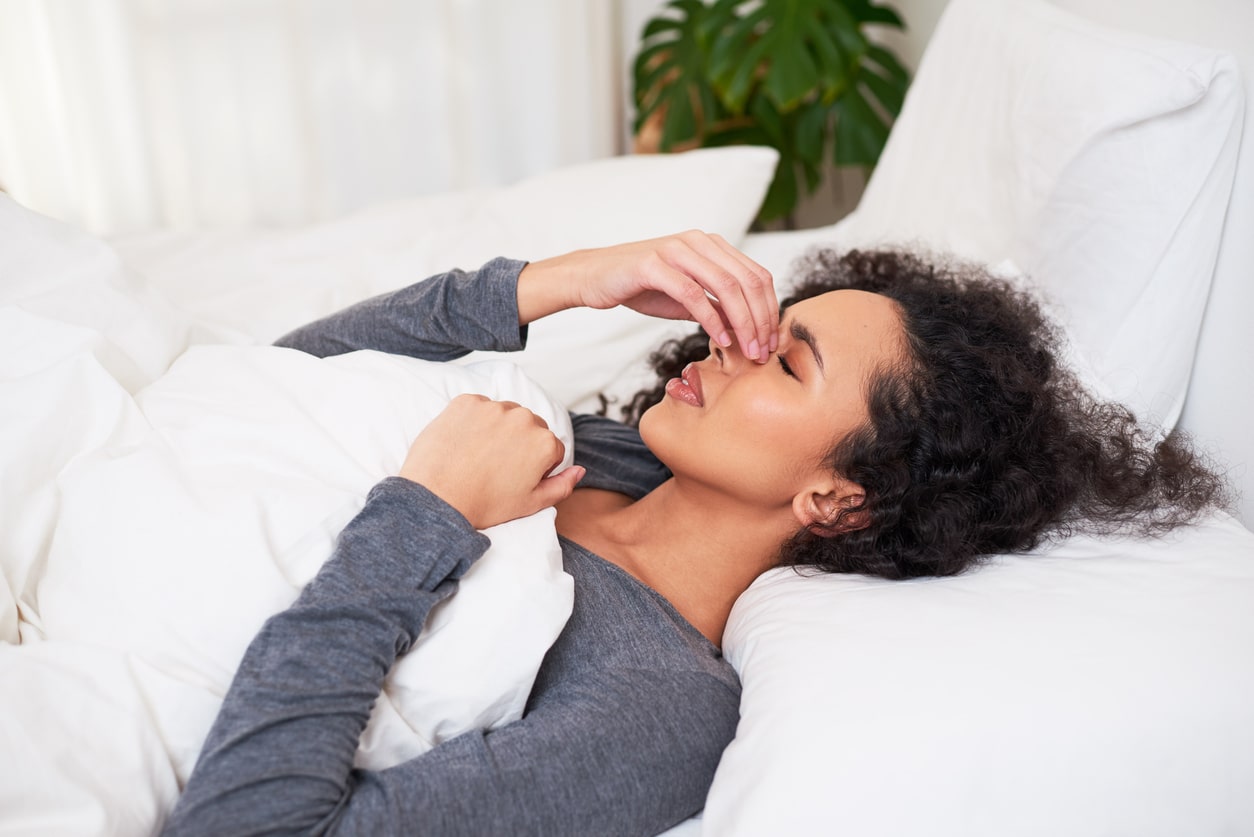 Woman touches nose while trying to sleep