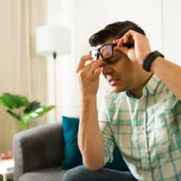 Man lifting his glasses to hold his sore sinuses