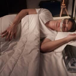 Man using CPAP mask and machine for sleep apnea treatment at home