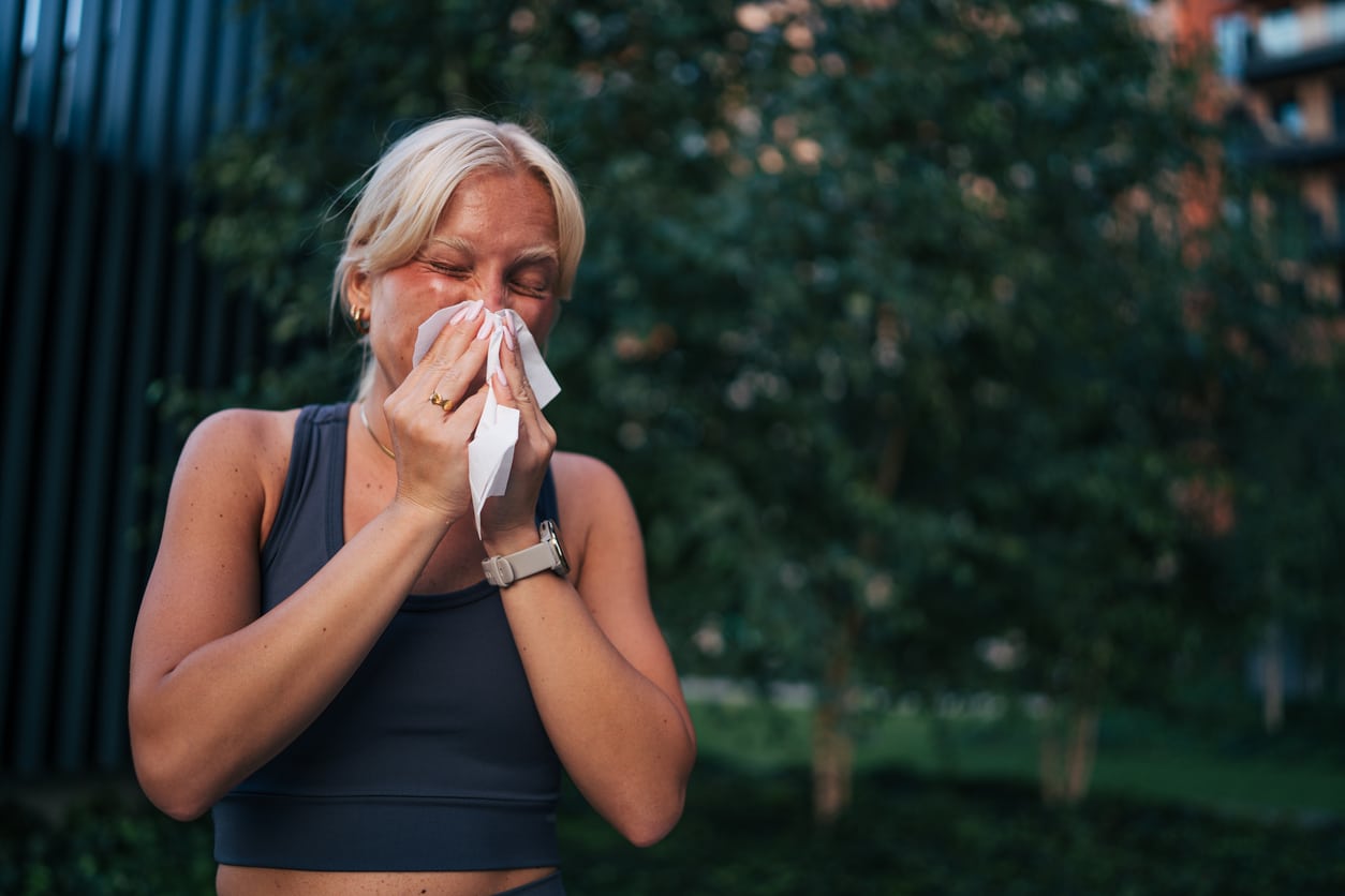 Young sporty woman blowing nose after training outdoors.